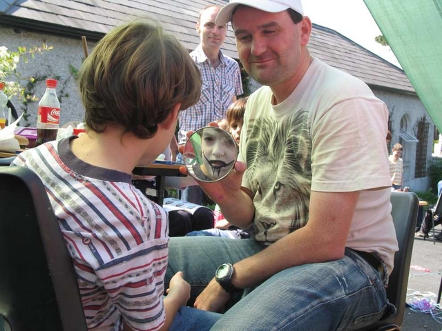 A young participant in Taney Parish Fete examines the Face Painting Work.