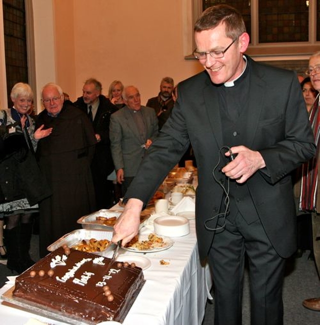 Canon Mark Gardner cuts the cake following his institution as the rector of the new parish of St Catherine and St James with St Audoen. 