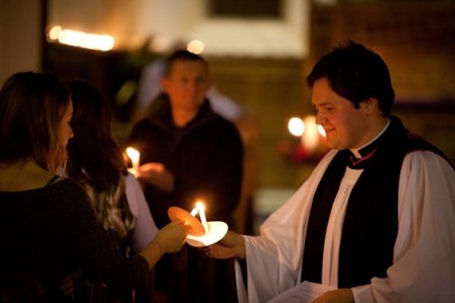 The rector of Zion Church, the Revd Stephen Farrell lighting candle at Zion carol service.