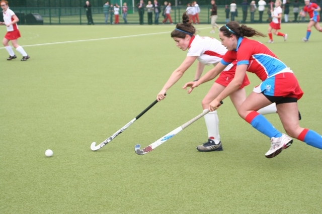 Pictured is action from a Hockey match between Alexandra College (red and white) and Mount Sackville (blue and red). The match was part of a programme of events to mark the official opening of two new pitches and one all purpose court in Alexandra College. The match was played on the Jenny Robinson (nee Telford) pitch named after a prominent ex-student. Alexandra College won the match 2-1.