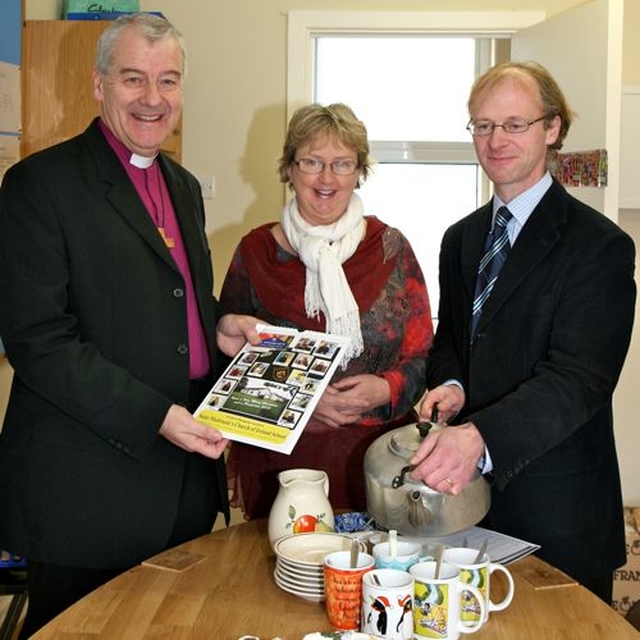 Principal of St Maelruain’s Church of Ireland School in Tallaght, Berna Daly, presents Archbishop Michael Jackson with a school calendar while chairman of the board of management, David Hutchinson Edgar, pours the tea. 