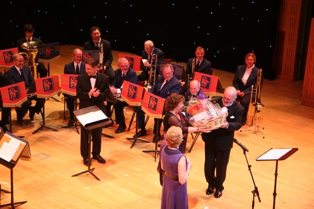 Senator David Norris receives a gift of 'Mothers' Union Macaroon' in appreciation for his work as MC at the Mothers' Union Award and variety show in the National Concert Hall in Dublin. Looking on is the Diocesan President of the Mothers' Union, Ann Walsh and Brian Daly and members of the Stedfast Brass Band. 