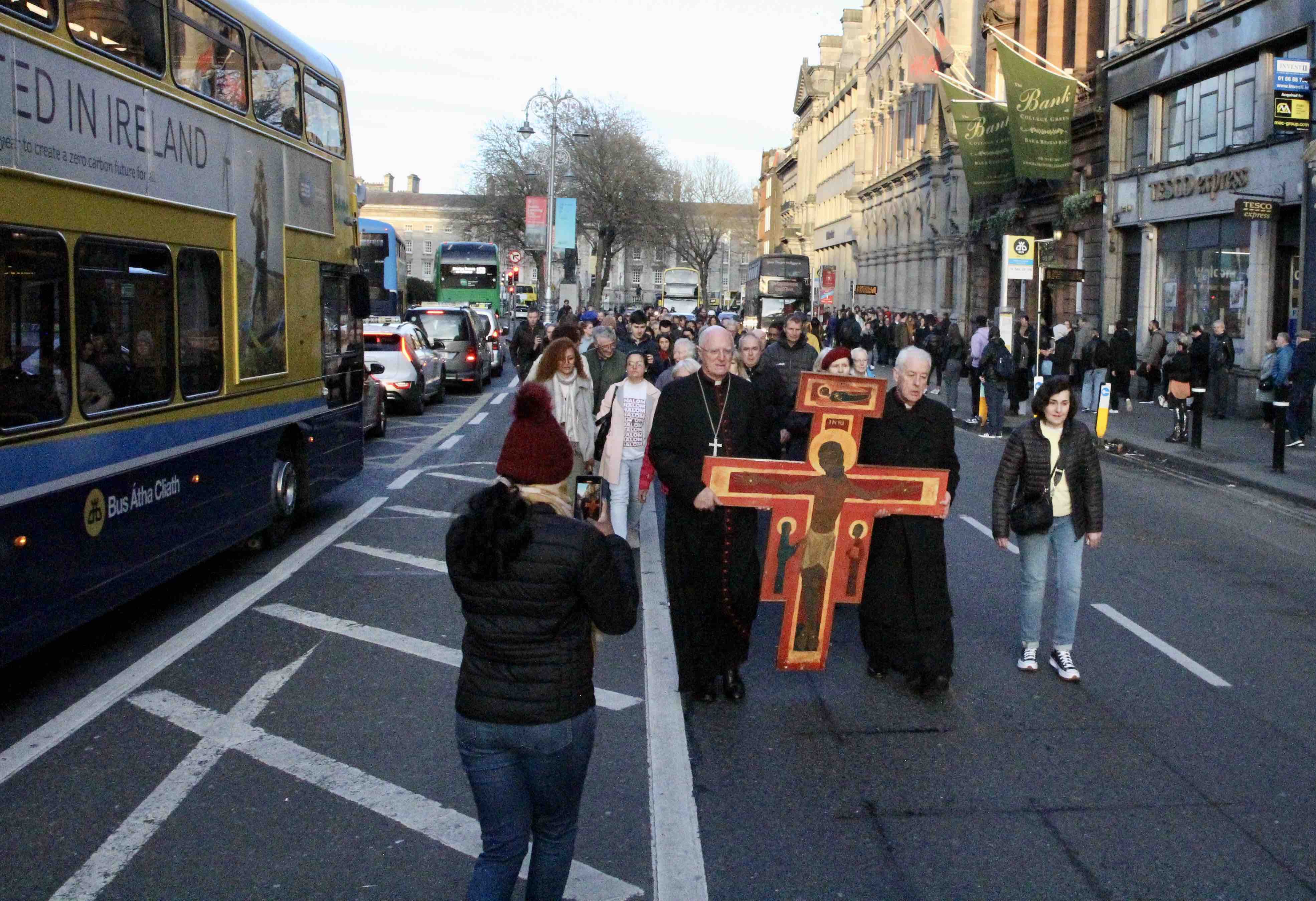 A passer-by on Dame Street photographs the Good Friday Walk of Witness.