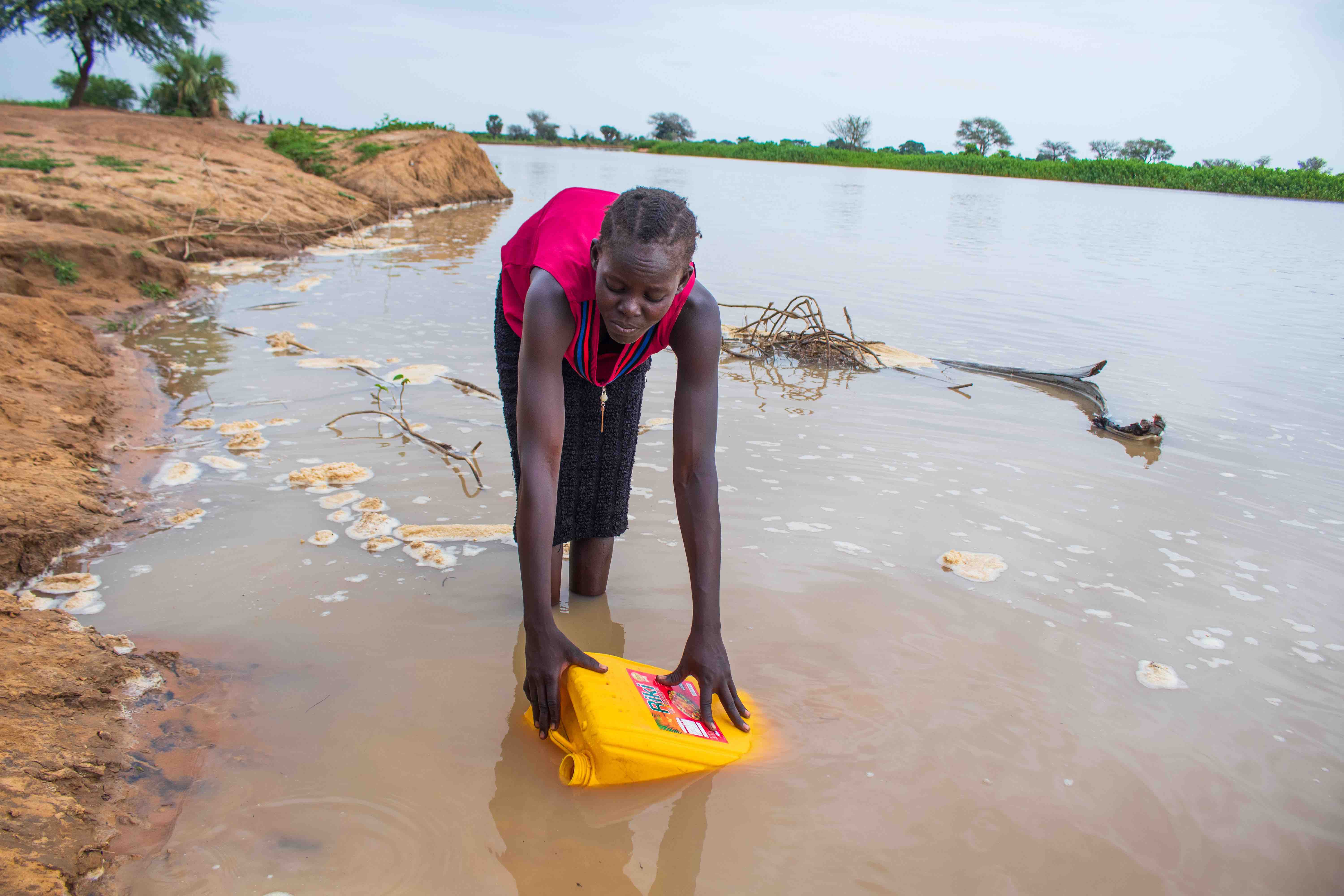 Adut demonstrates how she used to collect water from the river before the Christian Aid funded borehole brought clean water to her village. Credit: Christian Aid/Silvano Yokwe