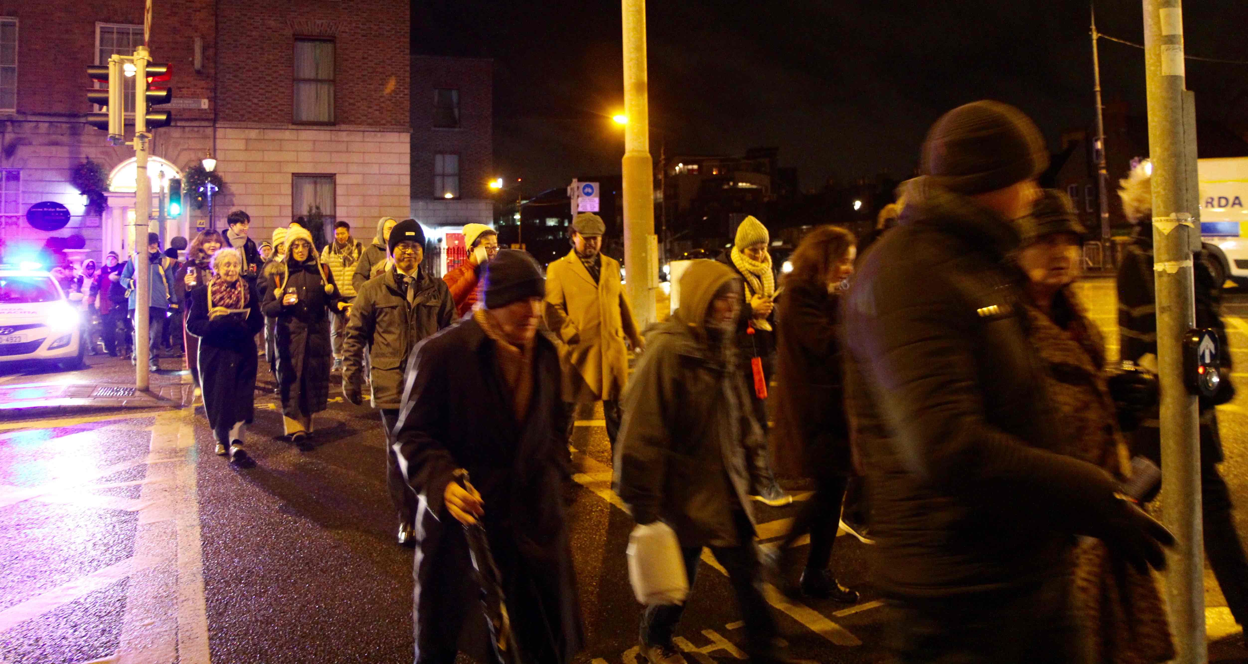 Participants in the Walk of Light cross Leeson Street with assistance from the Garda&iacute;.