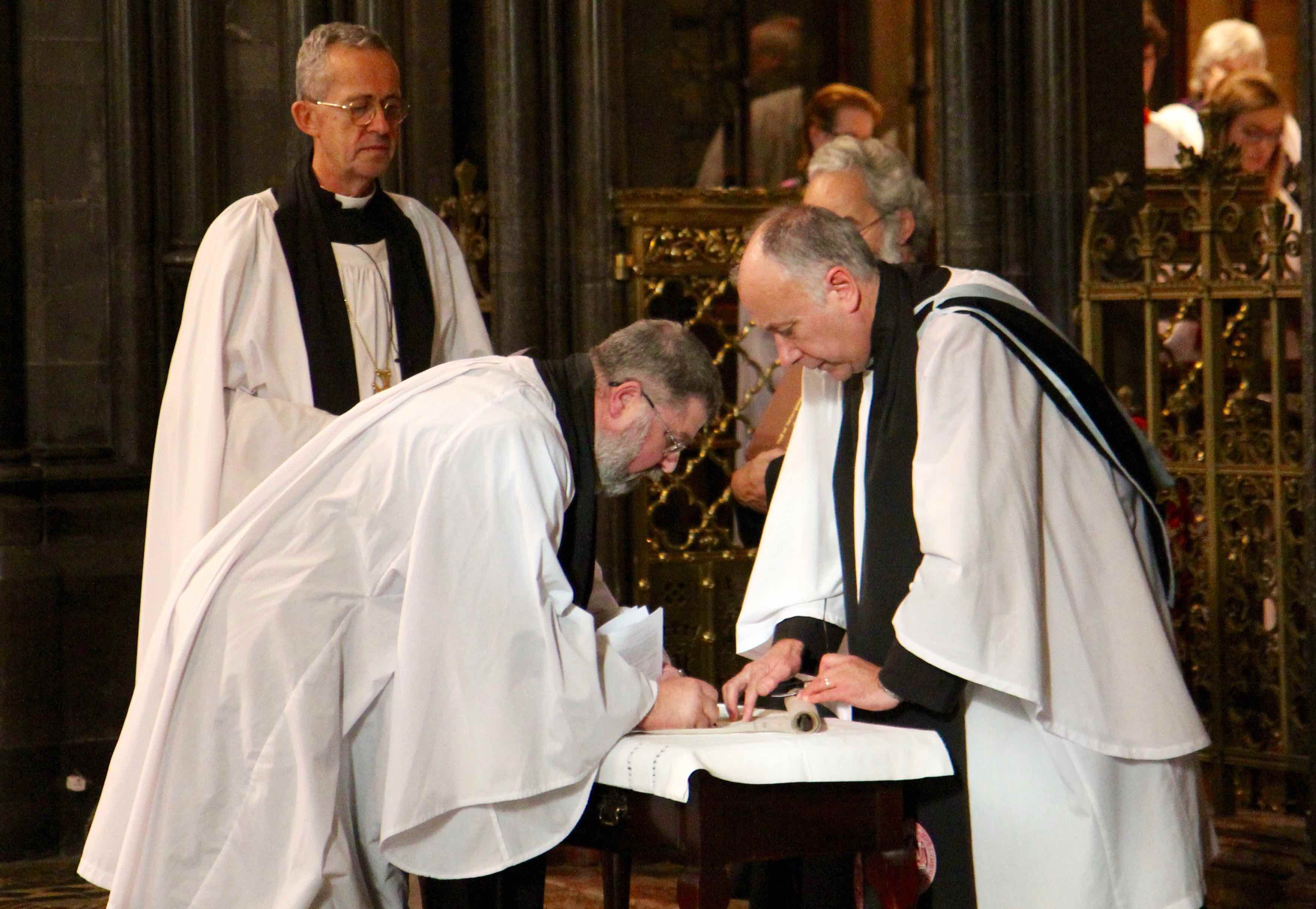 Archdeacon Neal O'Raw signs the Chapter Roll at his installation in Christ Church Cathedral Dublin in the presence of Canon Leonard Ruddock.