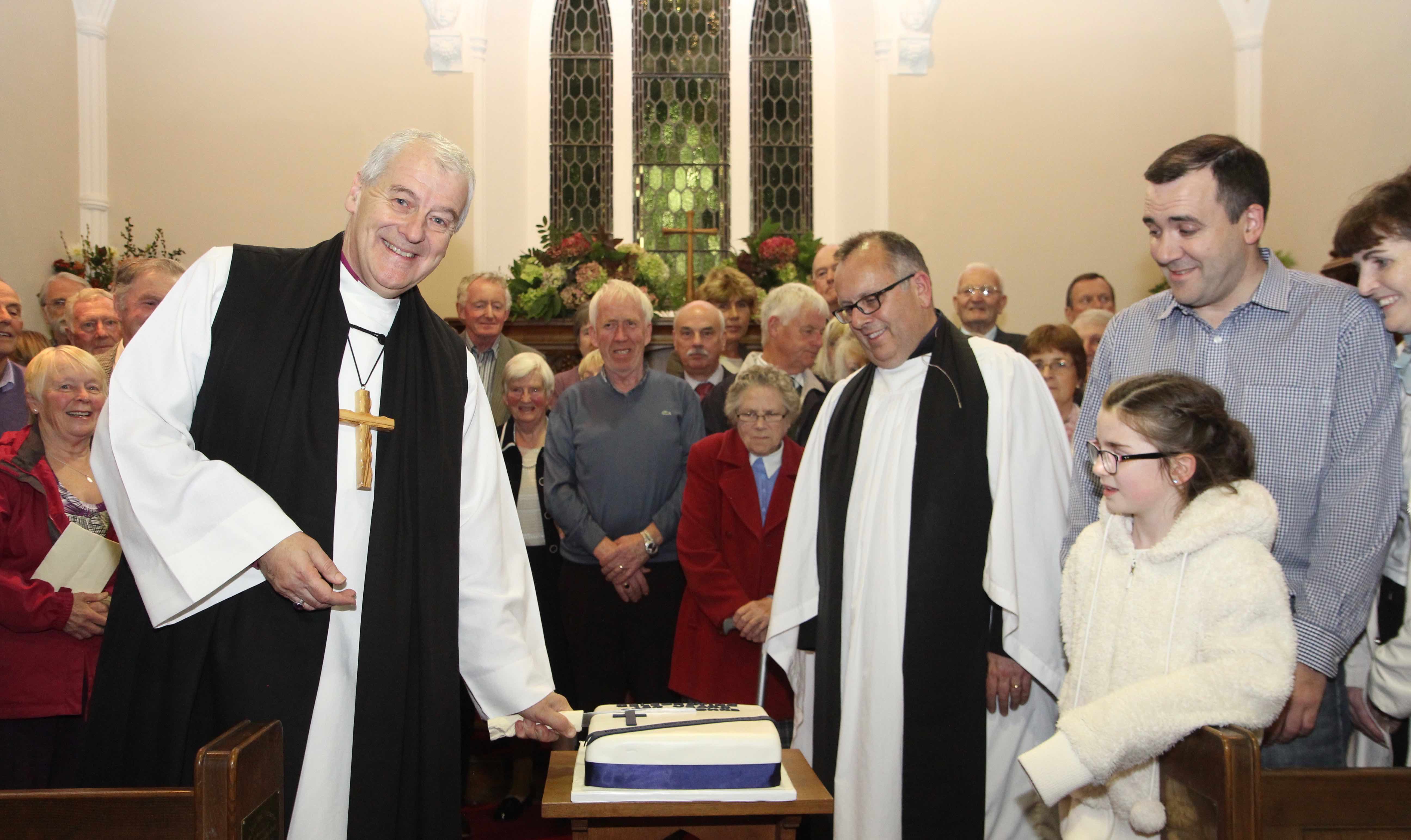 Archbishop Michael Jackson cuts the cake marking the 150th anniversary of St John's Church Laragh with the Rector, the Revd Brian O'Reilly and the congregation